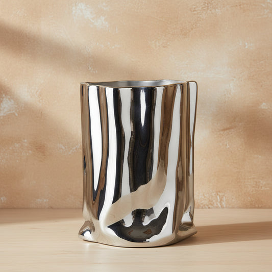 A polished metallic silver vase with a highly reflective, crumpled metal surface, shown against a plain white background.